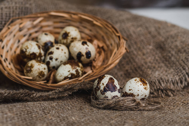 Quail eggs in a small basket on a rough linen napkin - Photo, Image