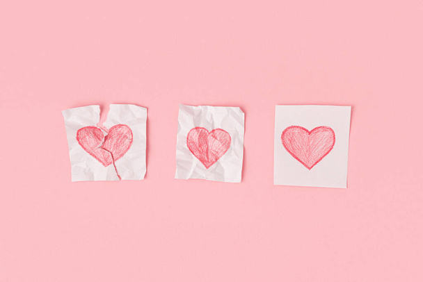 Three hearts drawn on pieces of paper on a pink background - Photo, image