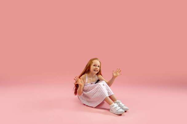 Childhood and dream about big and famous future. Pretty longhair girl isolated on coral pink background - Fotó, kép