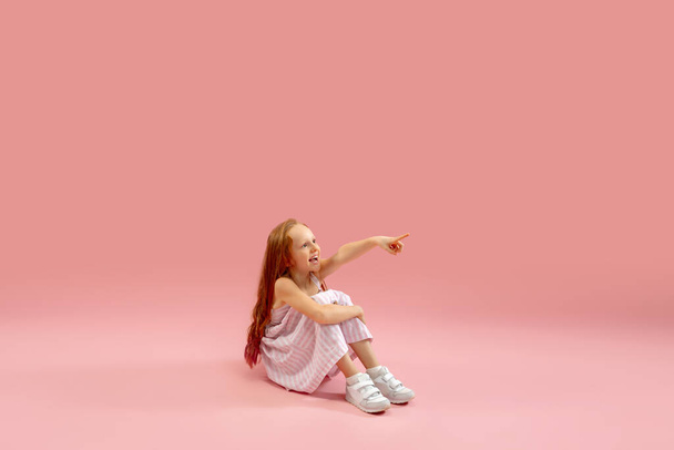Childhood and dream about big and famous future. Pretty longhair girl isolated on coral pink background - Foto, imagen