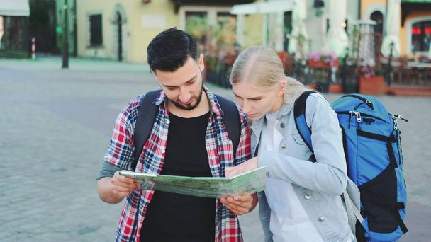 Turyści para trzyma mapę dla znalezienia nowego ciekawego miejsca do zwiedzania - Zdjęcie, obraz
