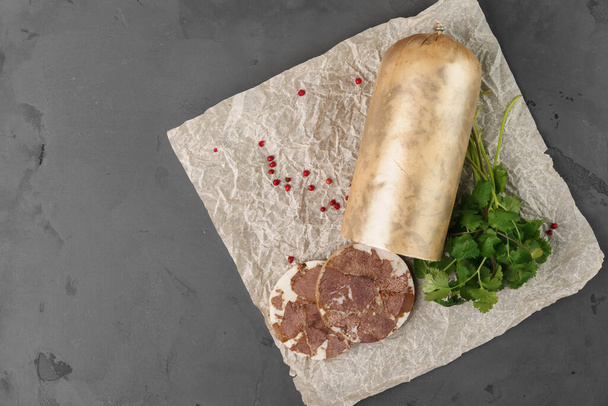 Liver sausage on parchment with parsley on gray background - Photo, image