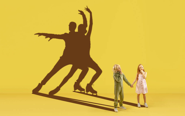Childhood and dream about big and famous future. Conceptual image with boy and girl and shadows of fit athletes, figure skating sportsmen. - Foto, imagen