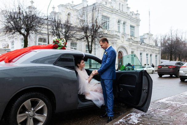 a noiva eo noivo estão sentados em um carro decorado com flores, o casamento cortege na cerimônia de casamento, duas pessoas felizes vão se casar - Foto, Imagem