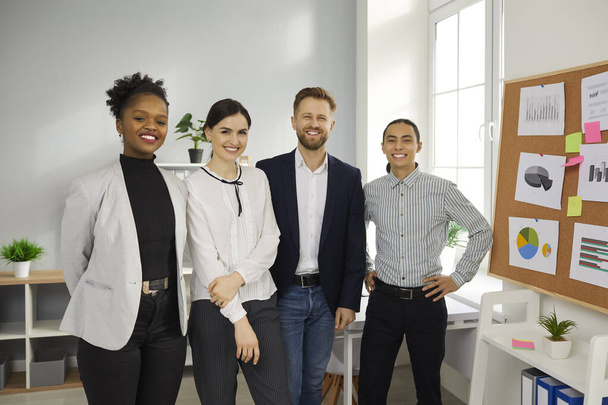 Équipe de gens d'affaires multiraciaux heureux debout dans le bureau de leur entreprise en démarrage - Photo, image