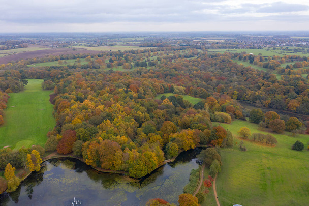 Luchtfoto in de herfst van de prachtige herfstkleuren van een park in Leeds, bekend als Roundhay Park in West Yorkshire UK, met een typisch Brits park en bossen langs een meer. - Foto, afbeelding