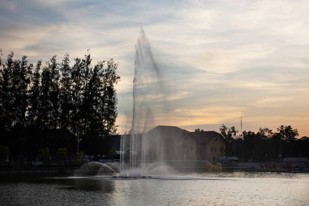 Stadtbild Udonthani Stadt und Landschaft Springbrunnen Spray in Teich Abendzeit für thailändische Menschen reisen Besuch und Ruhe entspannen im Nong Prajak Recreation Centre Public Park in Udon Thani, Thailand - Foto, Bild