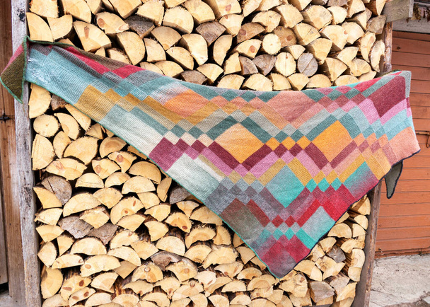 木製のトランクに並んでニットと暖かいスカーフ、カラフルなスカーフは、魅力的なスタイルで編まれ、手作り、ウールニット、薪の背景、冬の時間 - 写真・画像