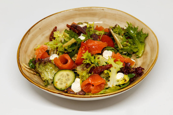 Salad with red fish and fresh vegetables on a handmade plate - Foto, immagini