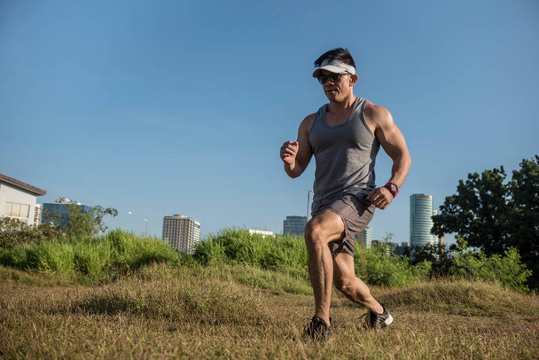 Egy sportos és izmos ázsiai férfi, aki testsúllyal előrenyomul a város melletti nyílt mezőn. Kereszt-tréning vagy calisthenics szabadban. - Fotó, kép
