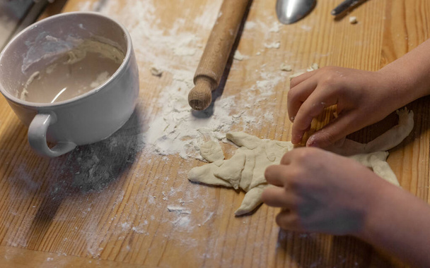 Mani di bambino formando una figura fatta con pasta di pane sul tavolo di legno. - Foto, immagini