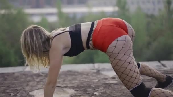 Girl dances twerk on the roof of an abandoned building. Girl in red shorts and tights in a cell. - Footage, Video