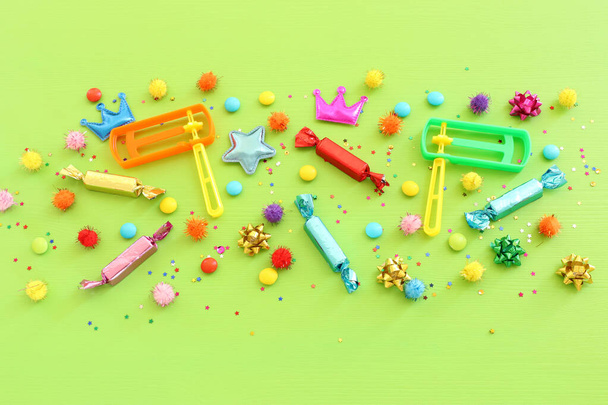Party colorful confetti, noise maker and candies over green wooden background . Top view, flat lay - Fotoğraf, Görsel