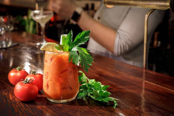 Bloody Mary Cocktail an der Theke mit Tomaten und Sellerie. Klassischer Cocktail. Hölzerner Hintergrund. - Foto, Bild