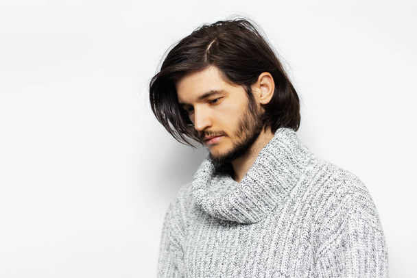 Studio portrait of young guy with long hair wearing turtleneck sweater on  white background. - Photo, Image