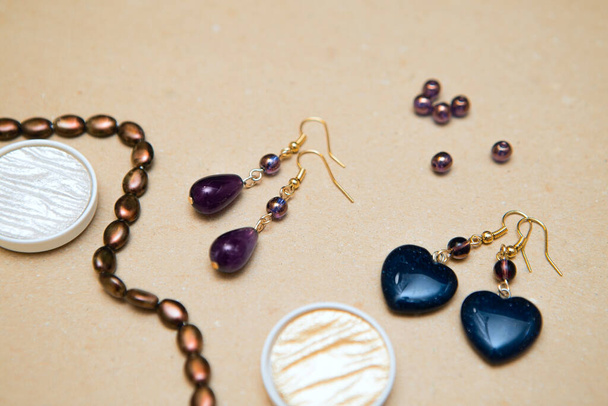 Handmade gemstone earrings. Amethysts, aventurine and glass beads on a cardboard background. Women's Jewelry - Foto, afbeelding