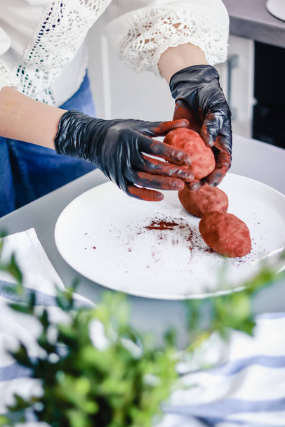 Konditor in Handschuhen rollt Kartoffelkuchen in Kakaopulver - Foto, Bild