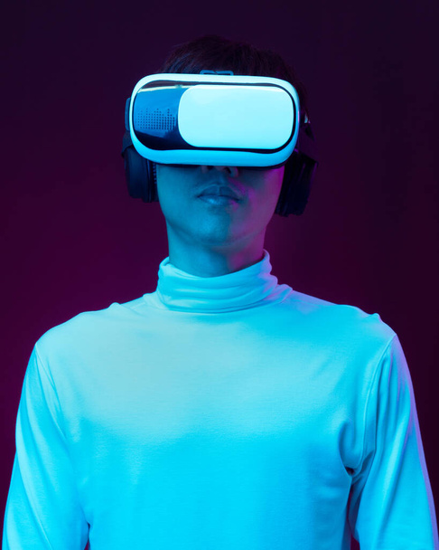Młody azjata człowiek w wirtualnej rzeczywistości gogle oglądanie 360 stopni wideo w świetle neonów, Technologia koncepcja. - Zdjęcie, obraz