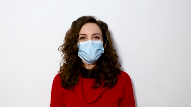 Portrait of a Beautiful Dark Haired Young Woman Wearing Protective Medical Face Mask and isolated white background. Safe and Happy Woman Practicing Social Distancing, Quarantine - Footage, Video