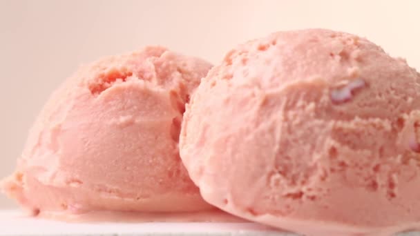 gros plan de deux boules de crème glacée rose tournant sur fond beige - Séquence, vidéo