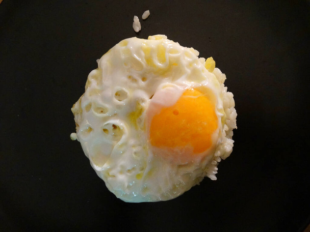Яйце лякає білим рисом на чорній страві
 - Фото, зображення