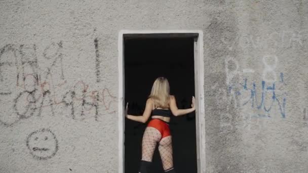 Dziewczyna tańczy twerk na dachu opuszczonego budynku. Dziewczyna w czerwonych spodenkach i rajstopach w celi. - Materiał filmowy, wideo