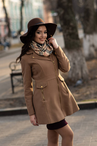 Belle jeune fille en manteau marron et écharpe se promenant dans la ville au printemps - Photo, image