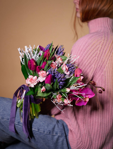 Piękna kobieta w różanym swetrze i dżinsy gospodarstwa kolorowy bukiet tulipanów, goździków i innych kwiatów. Walentynki, Międzynarodowe Dni Kobiet lub koncepcja Dzień Matki - Zdjęcie, obraz
