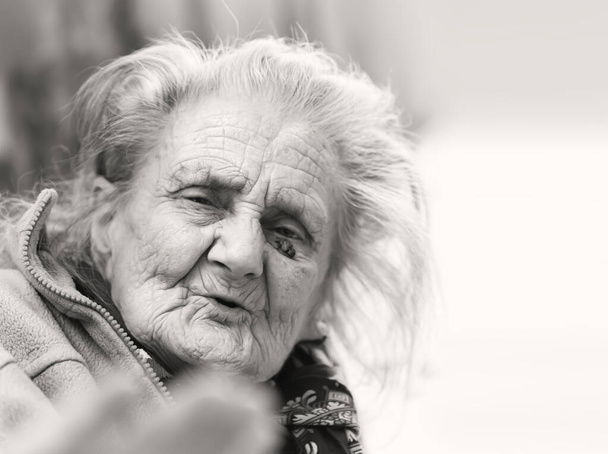 Old woman. Portrait of very old tired woman in depression sitting indoors on bed - Photo, Image