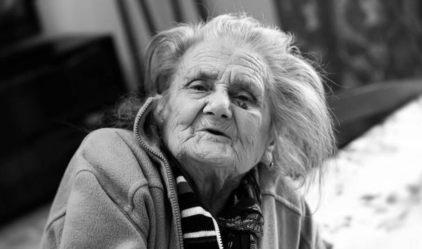 Oude vrouw. Portret van zeer oude vermoeide vrouw in depressie zittend binnen op bed - Foto, afbeelding