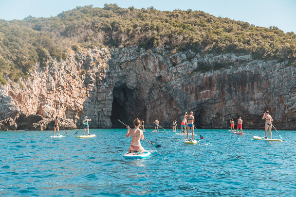 Touristen mit SUP Stand Up Paddle Brettern in der Nähe der Blauen Höhle, der schönsten Grotte Montenegros. - Foto, Bild