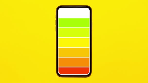 Stop bewegingsanimatiefotografie. Batterij opladen op het scherm van de smartphone, op de achtergrond van gele kleur. - Video