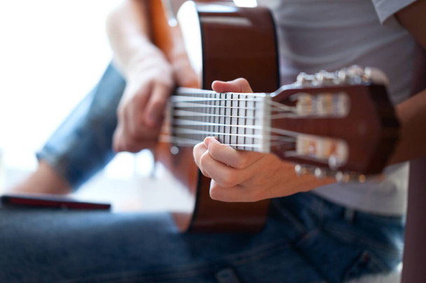 Closeup of hands teenager playing acoustic guitar. Have a hobby. Relaxing boy playing guitar. Soft focus. - Fotografie, Obrázek