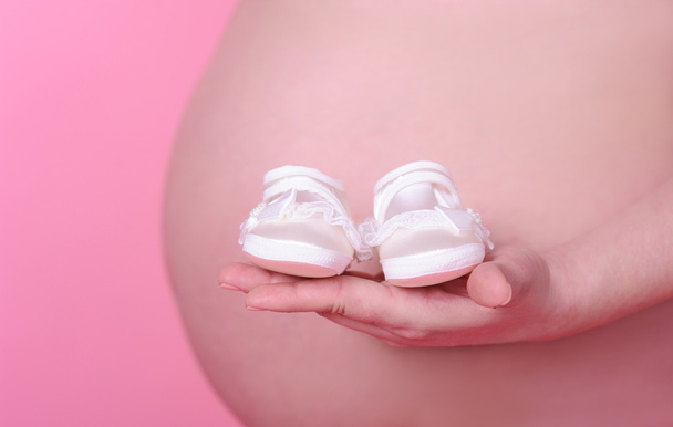έγκυος γυναίκα που κρατάει παιδικά παπούτσια - Φωτογραφία, εικόνα