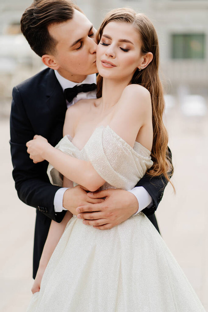 beautiful, gentle and happy bride and groom. man gently kisses womans face - Fotó, kép