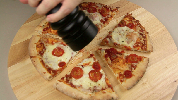 Młynek do pieprzu mielenie pieprzu na kawałki świeżej pizzy upieczone - Materiał filmowy, wideo