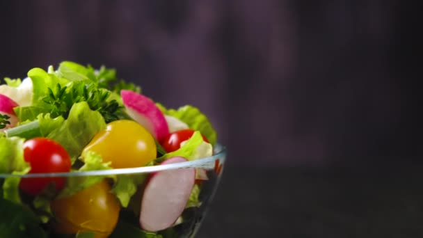 Čerstvý zeleninový salát z okurek, rajčat a salátu na černém pozadí - Záběry, video