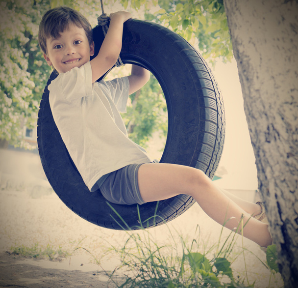 happy boy on swing outdoors - Фото, изображение