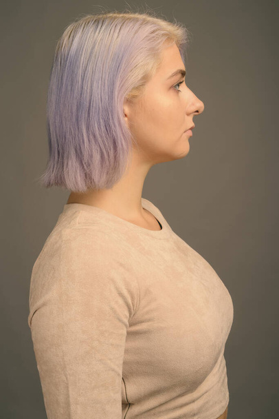 Nuori kaunis kapinallinen nainen värikkäillä hiuksilla harmaata taustaa vasten - Valokuva, kuva