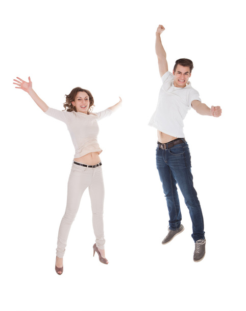 Couple In Casuals Jumping Over White Background - Fotó, kép
