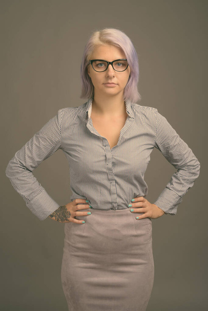 Giovane bella donna d'affari con i capelli corti colorati contro sfondo grigio - Foto, immagini