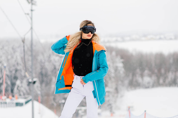 Donna in abbigliamento sportivo snowboarder posa in occhiali da sole con uno snowboard - Foto, immagini