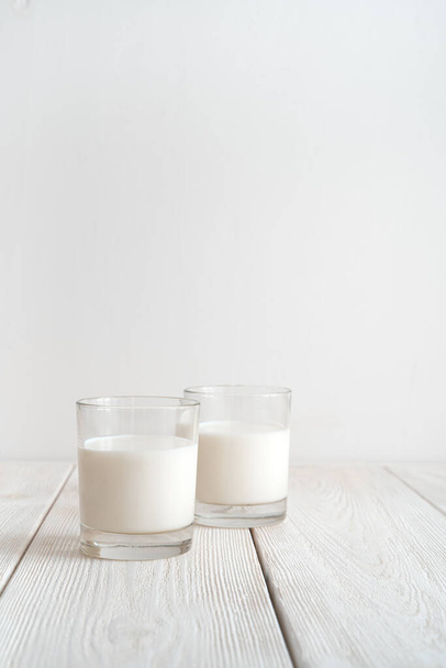 Due bicchieri di latte su sfondo bianco. Vista laterale con spazio di copia, orientamento verticale. - Foto, immagini
