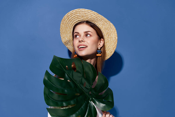 女性の帽子ヤシの葉で手高級エキゾチックな青の背景 - 写真・画像