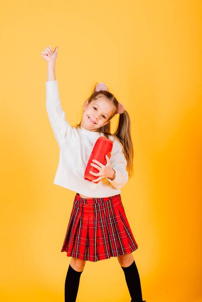 Young cute girl smiling and dancing with wireless portable speaker on yellow studio background. New year mood. - Foto, Imagem