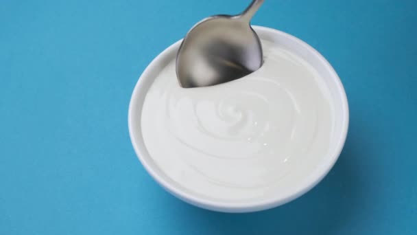 Bol de crème sure sur fond bleu, yaourt grec - Séquence, vidéo