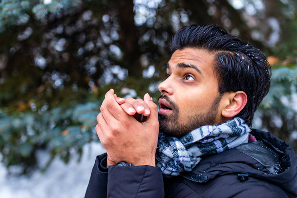 indian man enjoying snowflakes falling from upwards in forest - 写真・画像