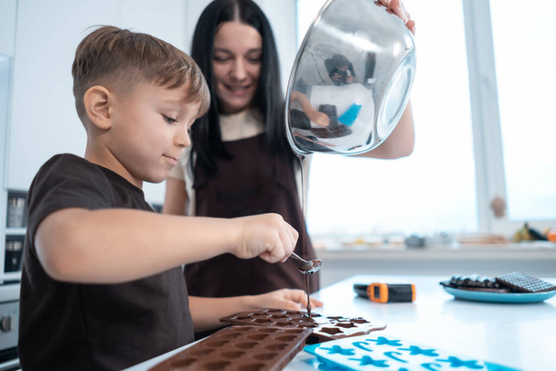 happy mother and kid making chocolate candies or sweets at home modern kitchen - Foto, Bild