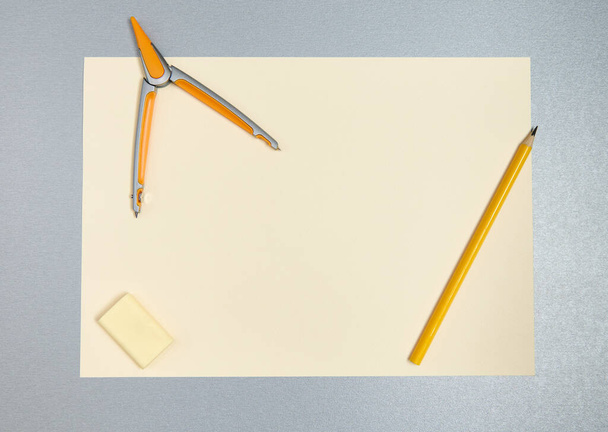 Vista superior de ferramentas amarelas para desenho. Lápis, bússola, borracha e folha de papel - Foto, Imagem
