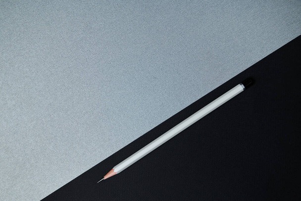 Ansicht von oben. Flache Lay-Zusammensetzung von Bürowerkzeugen. Grauer Bleistift und ein Teil schwarzes Papier auf grauem Hintergrund - Foto, Bild